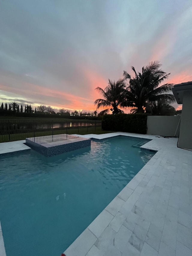 pool at dusk with a patio area