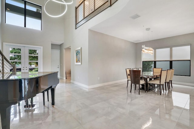 dining room featuring a towering ceiling, french doors, and a notable chandelier