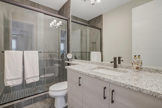 bathroom featuring toilet, vanity, an enclosed shower, and tile patterned flooring