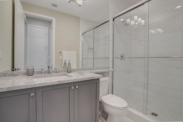 bathroom featuring toilet, vanity, and a shower with door