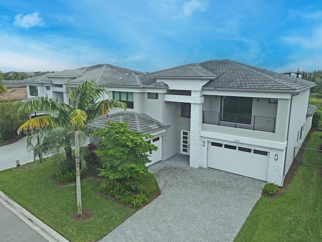 view of front of house featuring a front lawn, a garage, and a balcony