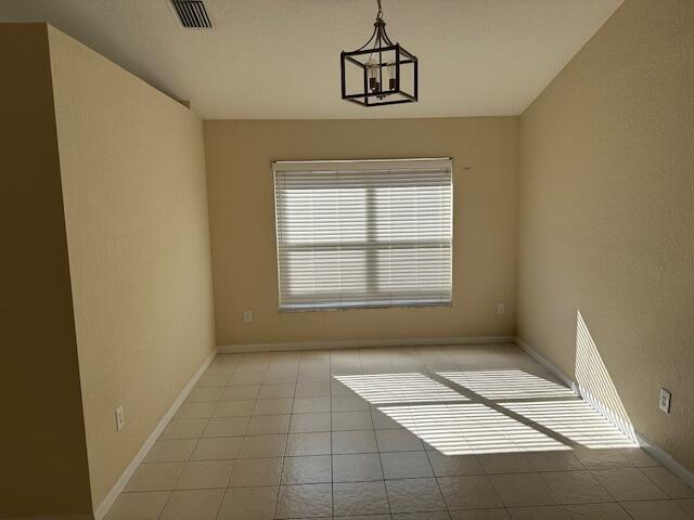 empty room with a chandelier and light tile patterned floors