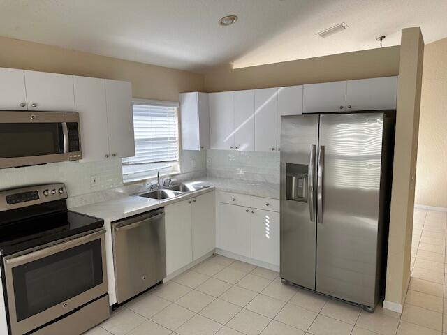 kitchen with backsplash, sink, white cabinets, and appliances with stainless steel finishes