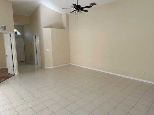 unfurnished room with ceiling fan, high vaulted ceiling, and light tile patterned floors