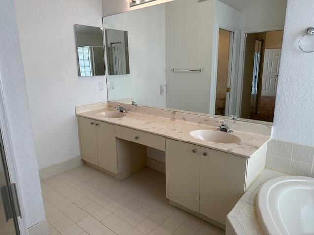 bathroom featuring tile patterned floors, vanity, toilet, and tiled bath