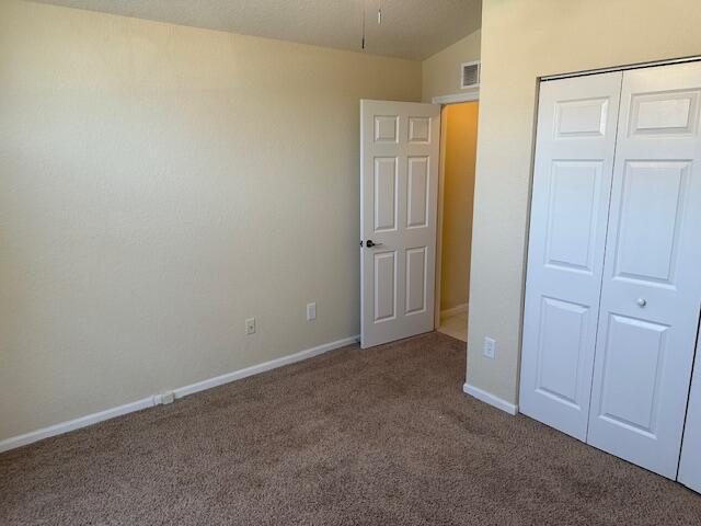 unfurnished bedroom with a closet, carpet, and lofted ceiling