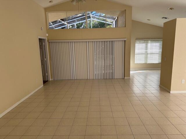 tiled empty room featuring high vaulted ceiling, ceiling fan, and a wealth of natural light