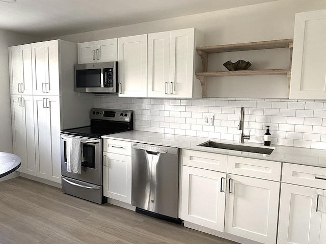 kitchen with white cabinets, appliances with stainless steel finishes, light hardwood / wood-style flooring, and sink