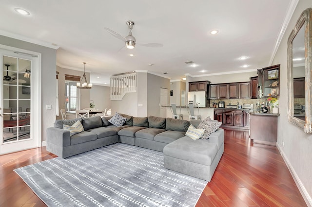 living room with ceiling fan with notable chandelier, dark hardwood / wood-style flooring, and ornamental molding