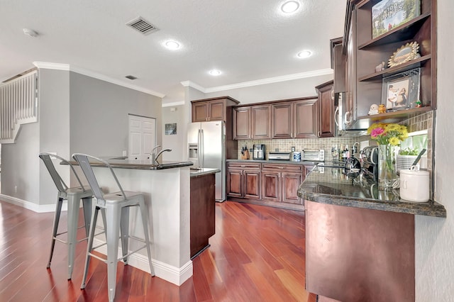 kitchen with a kitchen bar, dark wood-type flooring, crown molding, stainless steel fridge with ice dispenser, and a kitchen island