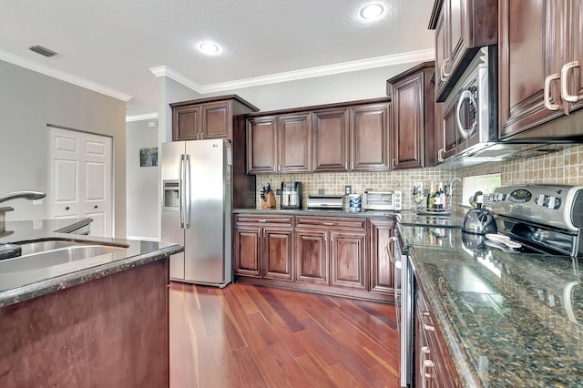 kitchen featuring sink, dark stone countertops, ornamental molding, appliances with stainless steel finishes, and tasteful backsplash