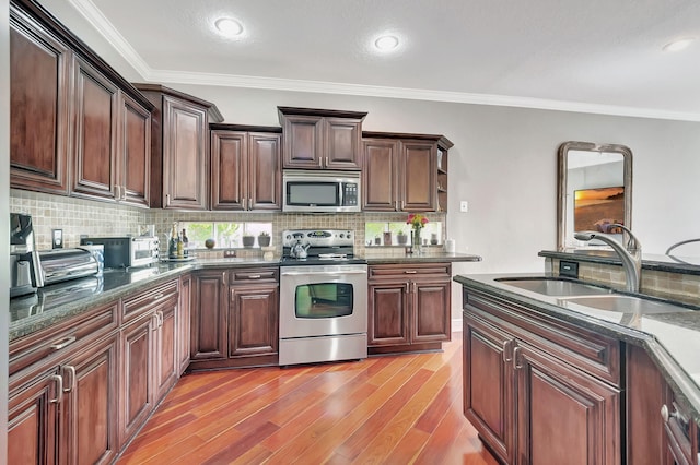 kitchen with decorative backsplash, sink, stainless steel appliances, and light wood-type flooring