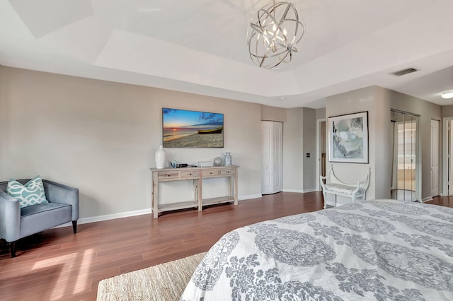 bedroom featuring hardwood / wood-style flooring, a notable chandelier, and a raised ceiling