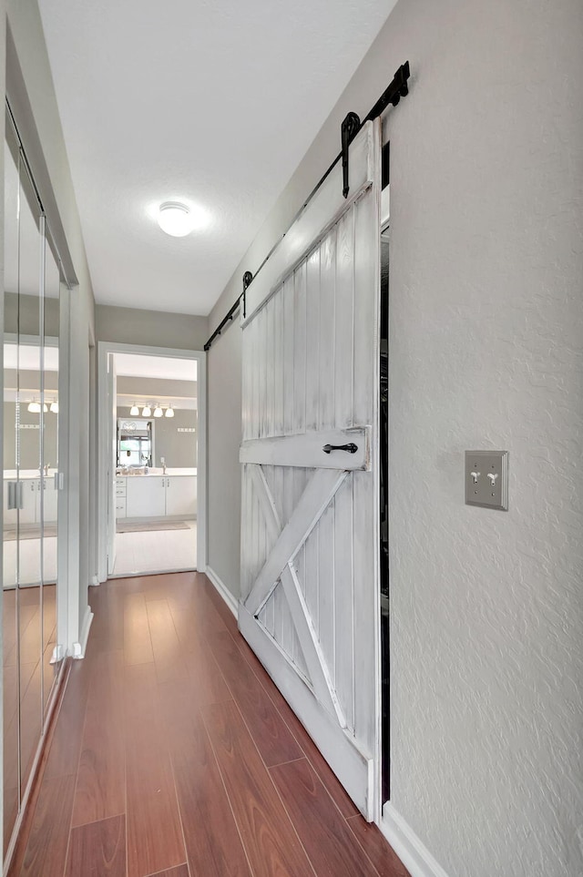 corridor with a barn door and dark hardwood / wood-style floors