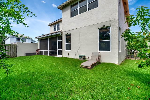 rear view of property featuring a lawn and a sunroom