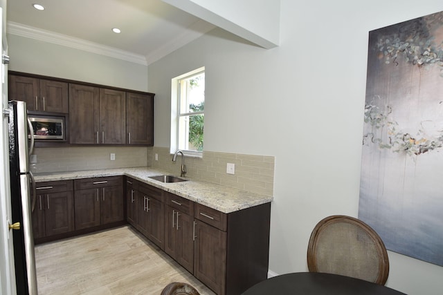 kitchen featuring light stone countertops, sink, tasteful backsplash, crown molding, and light hardwood / wood-style floors