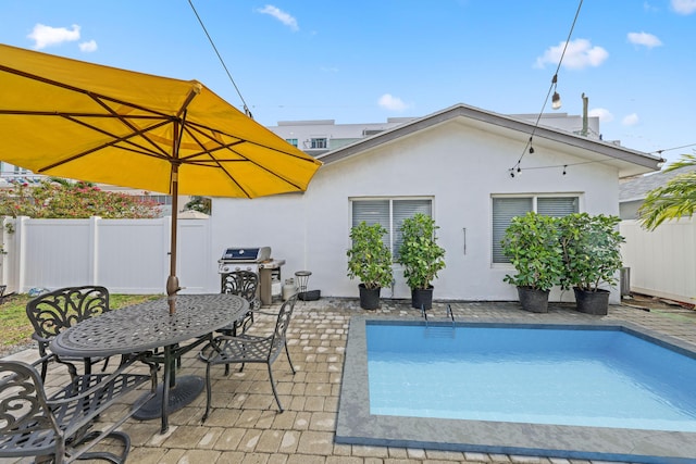 view of swimming pool featuring a grill and a patio