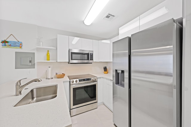 kitchen with light stone countertops, white cabinetry, sink, and appliances with stainless steel finishes