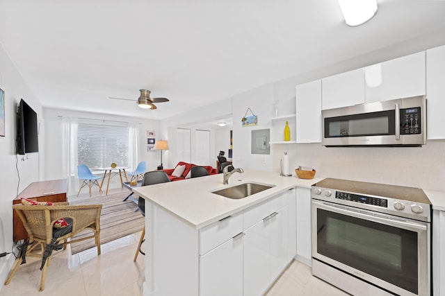 kitchen with kitchen peninsula, appliances with stainless steel finishes, white cabinets, and sink