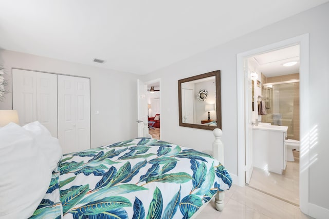 bedroom with a closet, light tile patterned floors, and ensuite bath