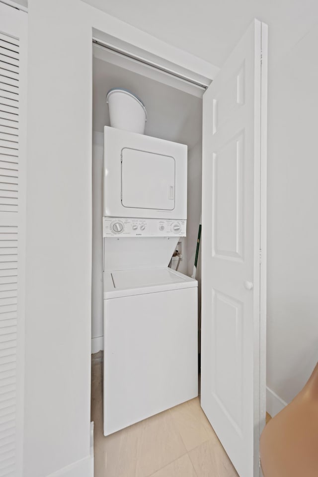 laundry area featuring light tile patterned floors and stacked washer and clothes dryer