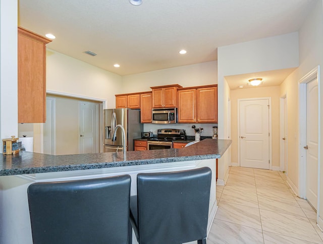 kitchen with a kitchen bar, kitchen peninsula, and stainless steel appliances