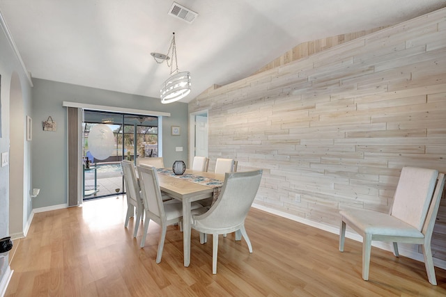 dining area with a chandelier, lofted ceiling, and light hardwood / wood-style flooring