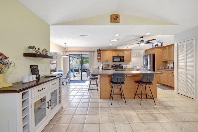 kitchen with appliances with stainless steel finishes, ceiling fan, a kitchen breakfast bar, and sink