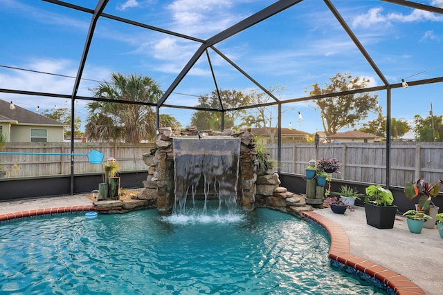 view of swimming pool with pool water feature, glass enclosure, and a patio