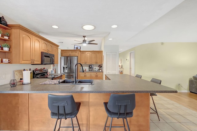 kitchen with sink, a breakfast bar area, light wood-type flooring, kitchen peninsula, and stainless steel appliances