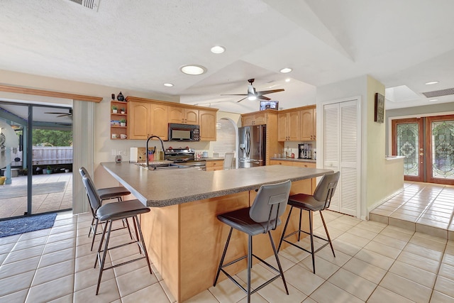 kitchen featuring french doors, a kitchen breakfast bar, sink, kitchen peninsula, and stainless steel appliances