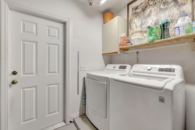 clothes washing area with washer and dryer and cabinets