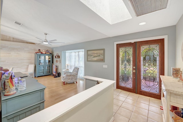 tiled entrance foyer with ceiling fan, wood walls, lofted ceiling, and french doors