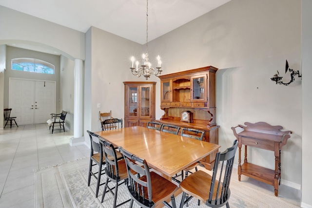 dining area with a towering ceiling, light tile patterned flooring, and a notable chandelier