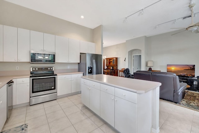 kitchen featuring a center island, ceiling fan, light tile patterned floors, appliances with stainless steel finishes, and white cabinetry