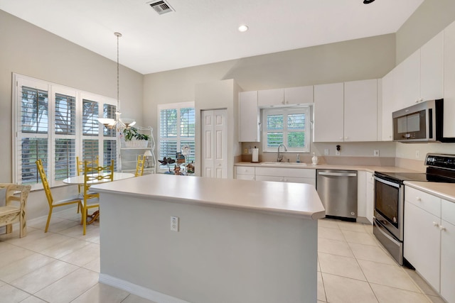 kitchen featuring white cabinets, sink, stainless steel appliances, and hanging light fixtures