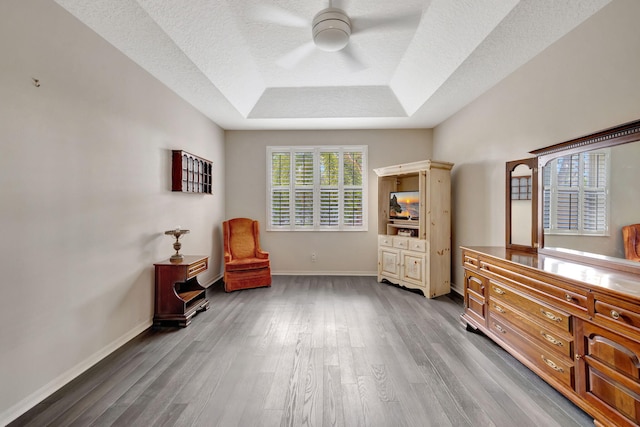 sitting room with hardwood / wood-style flooring, ceiling fan, a textured ceiling, and a tray ceiling