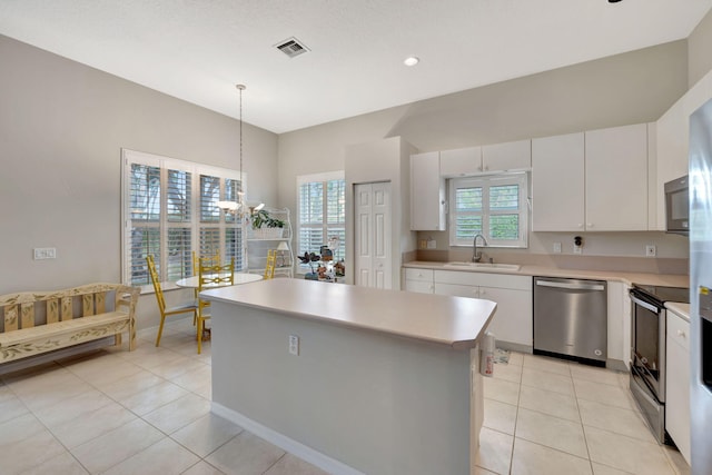 kitchen with stainless steel appliances, sink, decorative light fixtures, a center island, and white cabinetry