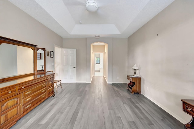 interior space with a raised ceiling, a textured ceiling, and light hardwood / wood-style flooring