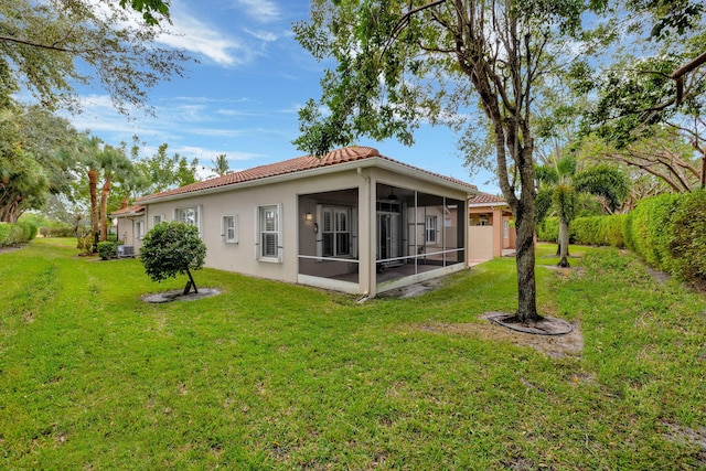 rear view of house with a sunroom, a yard, and cooling unit