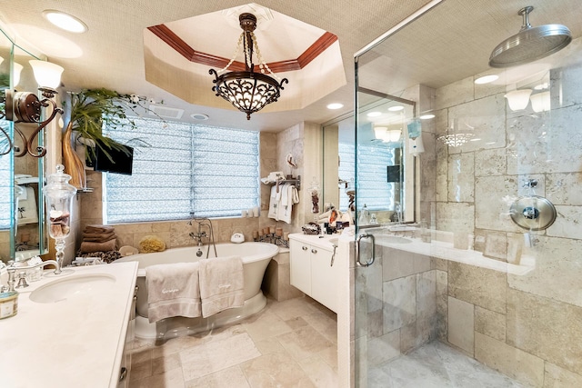 bathroom featuring a tray ceiling, a wealth of natural light, plus walk in shower, and vanity