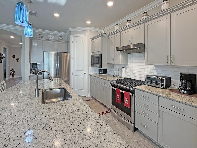 kitchen with tasteful backsplash, light stone countertops, appliances with stainless steel finishes, and sink