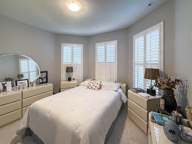 bedroom featuring light tile patterned floors and a textured ceiling