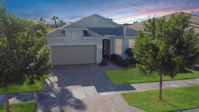 single story home featuring a garage and a lawn