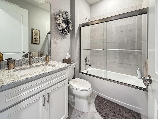 full bathroom featuring bath / shower combo with glass door, vanity, tile patterned floors, and toilet