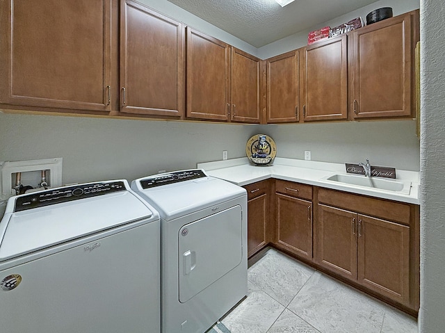 washroom with separate washer and dryer, sink, cabinets, light tile patterned floors, and a textured ceiling