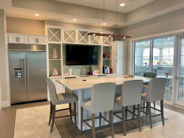 bar featuring white cabinetry, built in refrigerator, hanging light fixtures, and light tile patterned floors