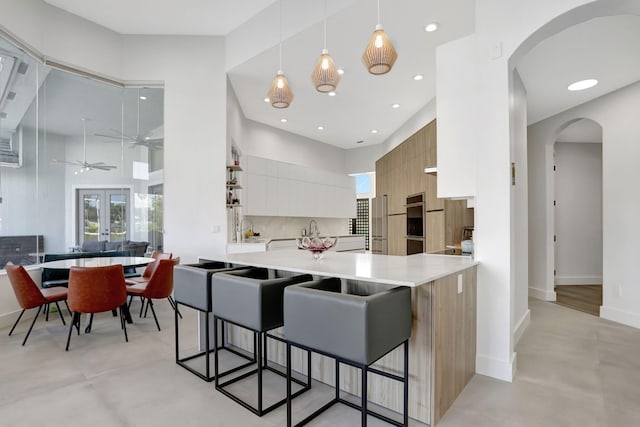 kitchen featuring white cabinetry, ceiling fan, kitchen peninsula, a breakfast bar area, and decorative backsplash