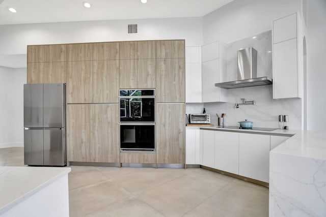 kitchen with light stone countertops, backsplash, wall chimney exhaust hood, black appliances, and white cabinetry