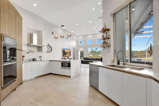 kitchen featuring white cabinetry, sink, stainless steel appliances, wall chimney range hood, and tasteful backsplash